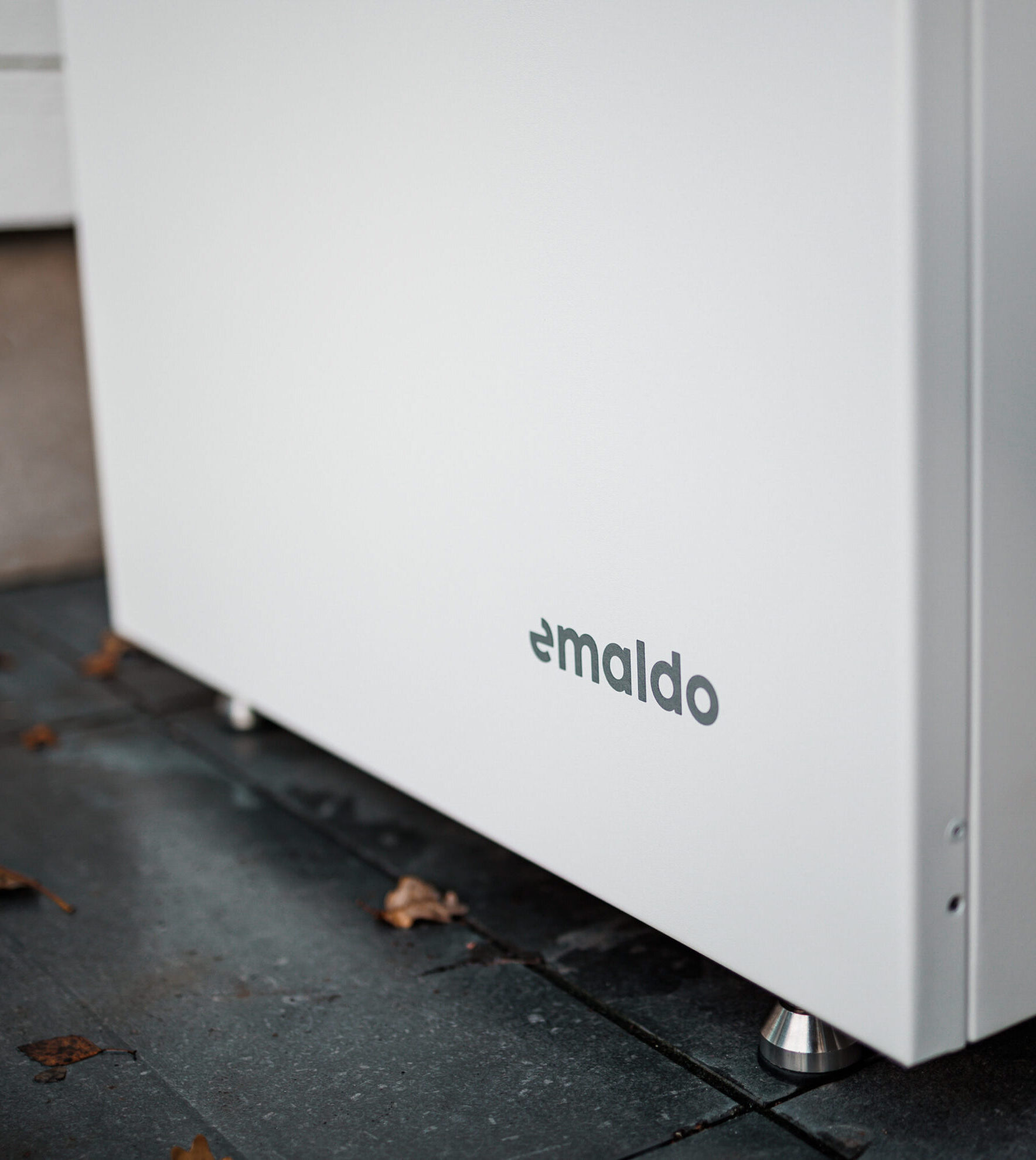Batterilagring 20 Närbild på Emaldo-batterilagring på hembatteri installerat i Solna – omgiven av höstlöv på stensatt uteplats.